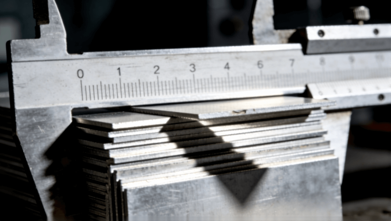 微距攝影展示鋁基板厚度公差，卡尺測量下參差交錯，側光凸顯縫隙與陰影